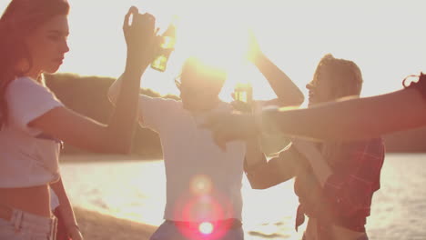 The-students-are-enjoying-summer-open-air-party-on-the-beach-with-beer.-They-are-dancing-on-the-lake-coast-and-having-a-great-time-on-the-nature.